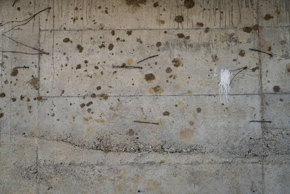A detailed view of a weathered concrete wall with exposed rebar, showcasing industrial textures.